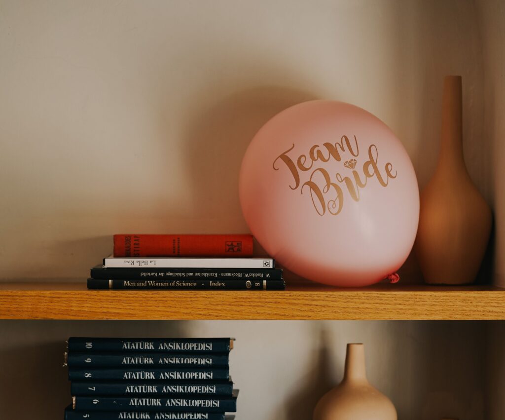 balon z napisem Team Bride na drewnianej półce wśród książek